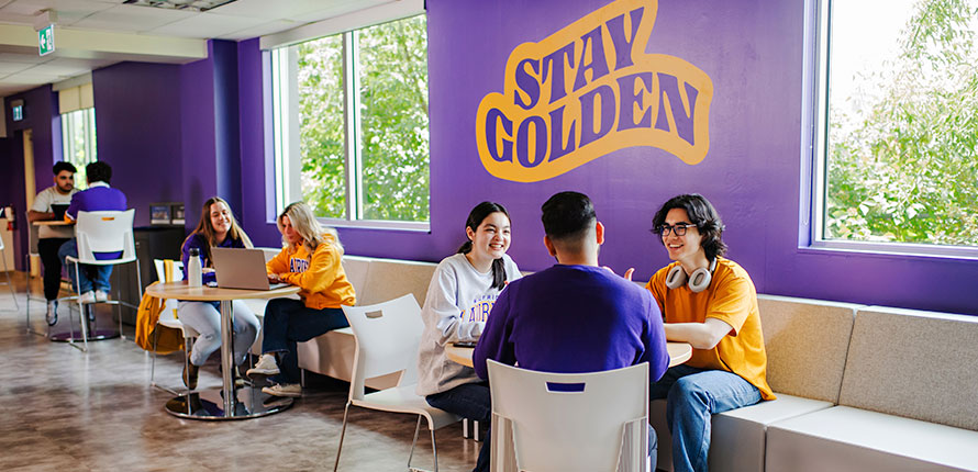 Students studying in front of "Stay Golden" sign