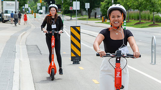 Two students using the neuron e-scooters.