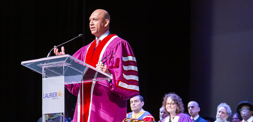 Chancellor Nadir Patel in regalia on stage giving speech