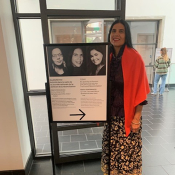 Barbara standing next to sign for event