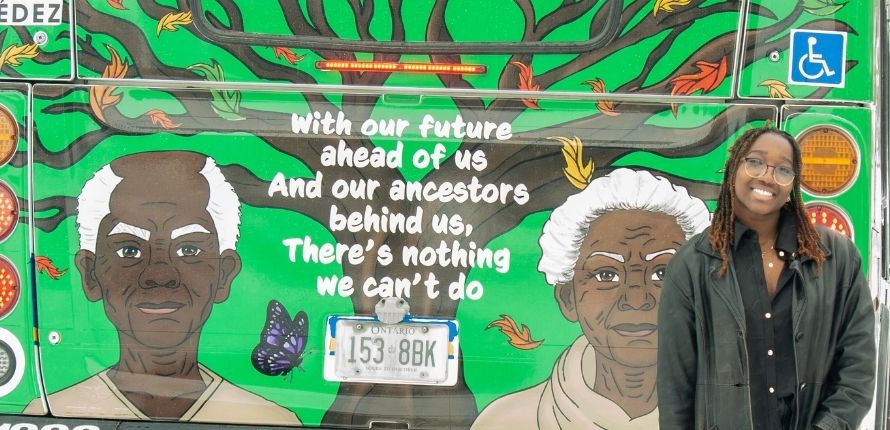 Vanessa Nkansah-Okoree stands in front of a Grand River Transit bus displaying her design for Black History Month.