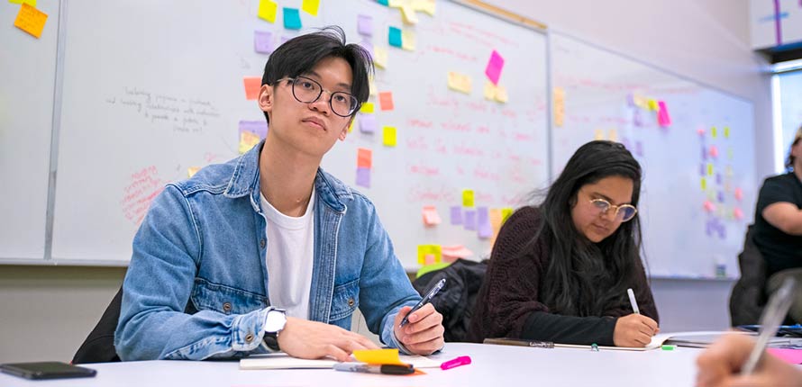 male and female student in classroom taking notes