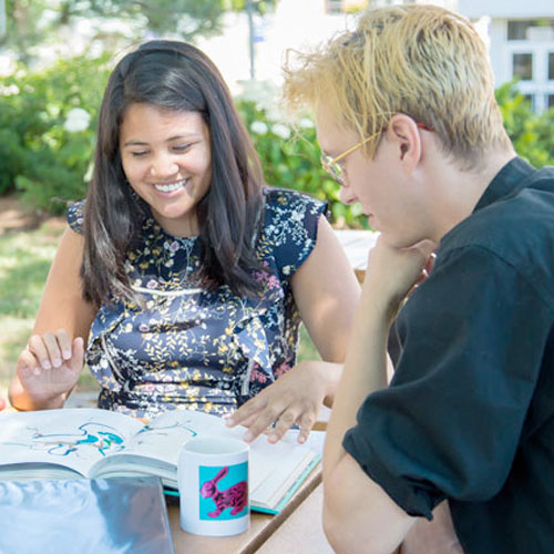 Female and male student studying outside.