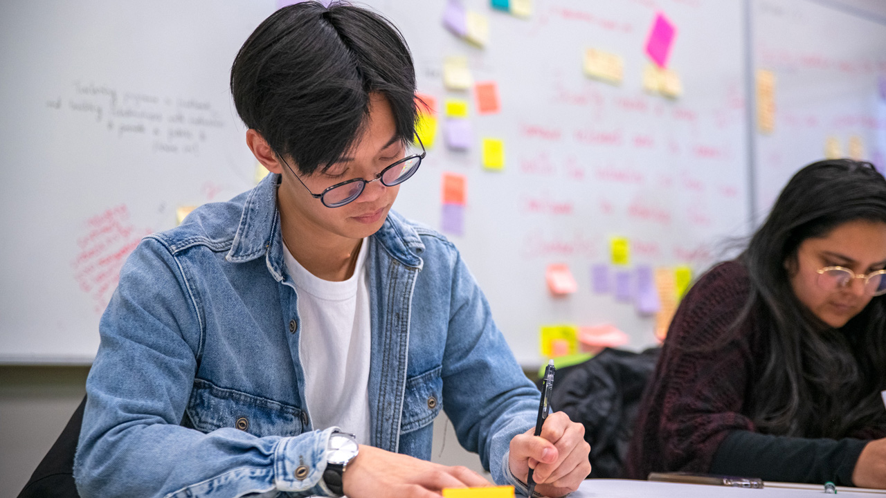 male and female student taking notes in class